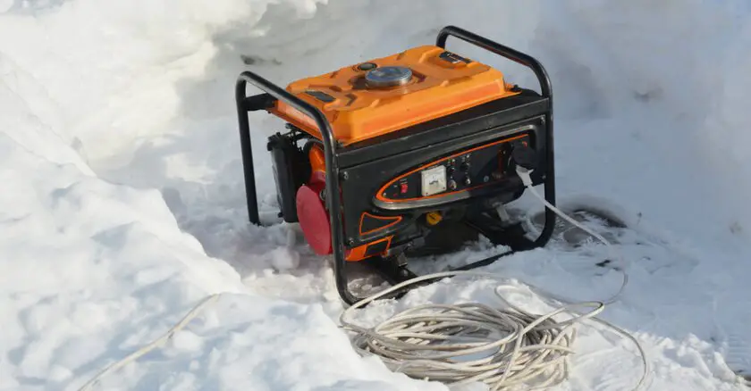 Portable generator in snow with cables.